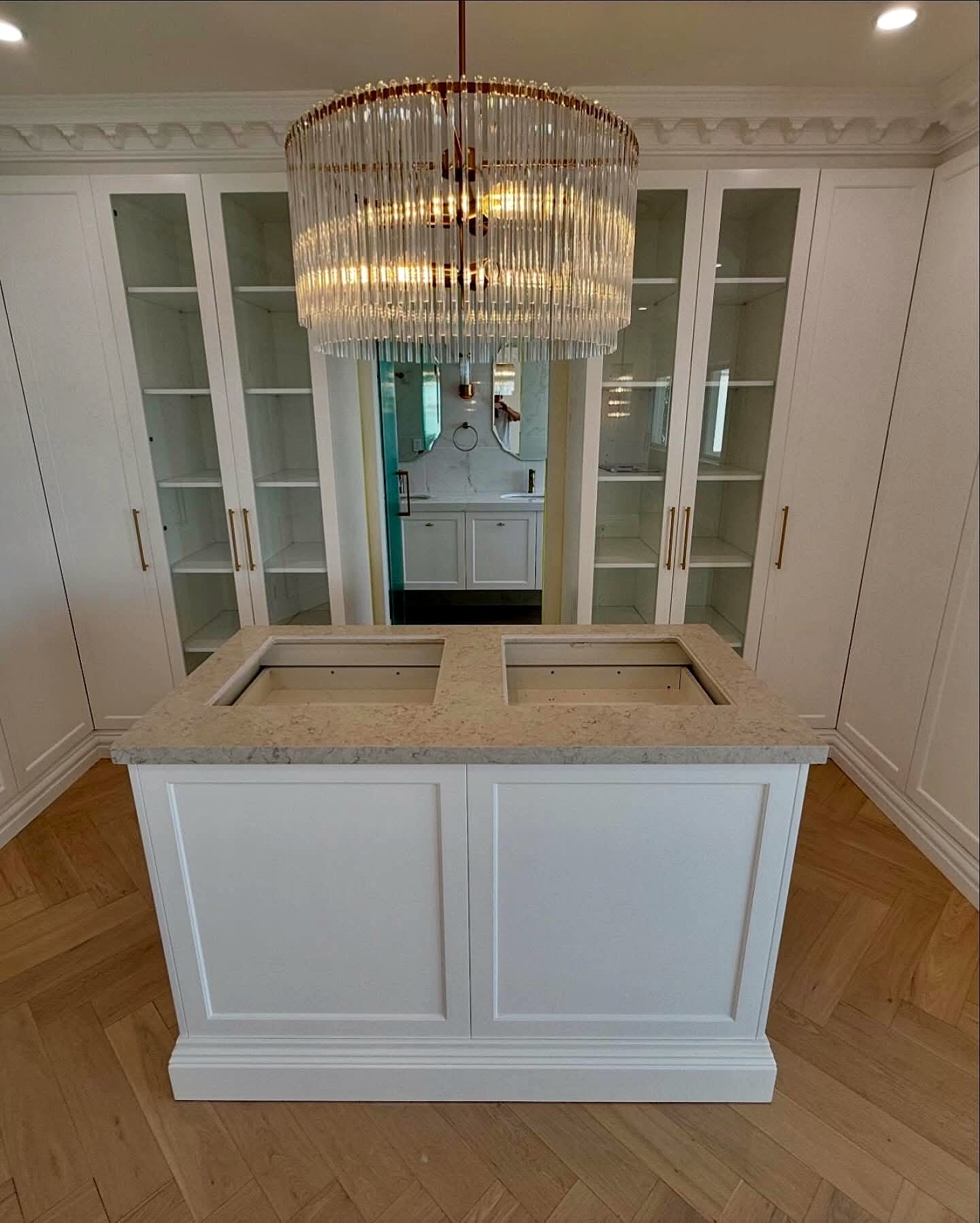 Kitchen island beneath a chandelier, herringbone flooring underfoot