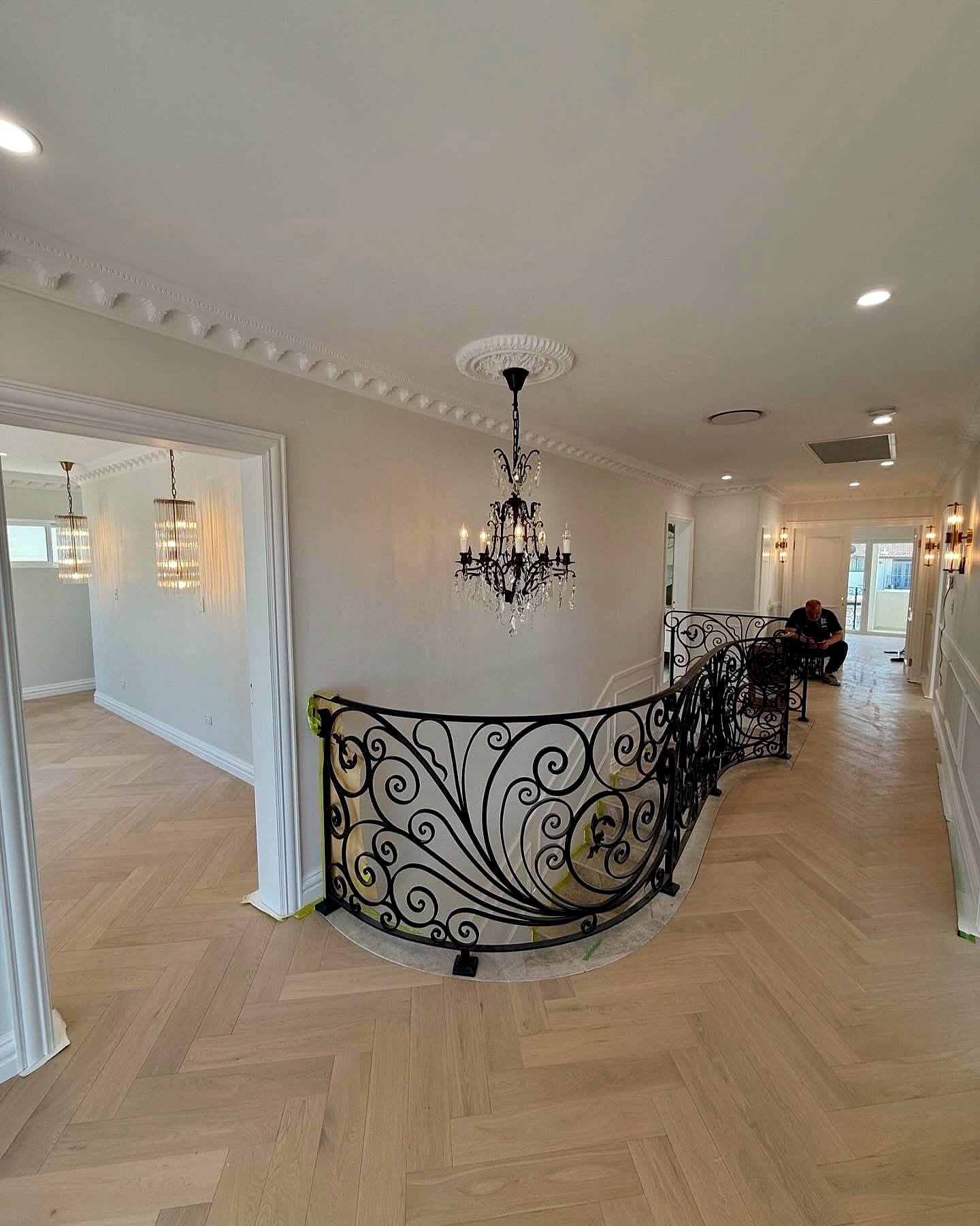 Upstairs landing with a scrolled iron balustrade and cornice work over herringbone boards