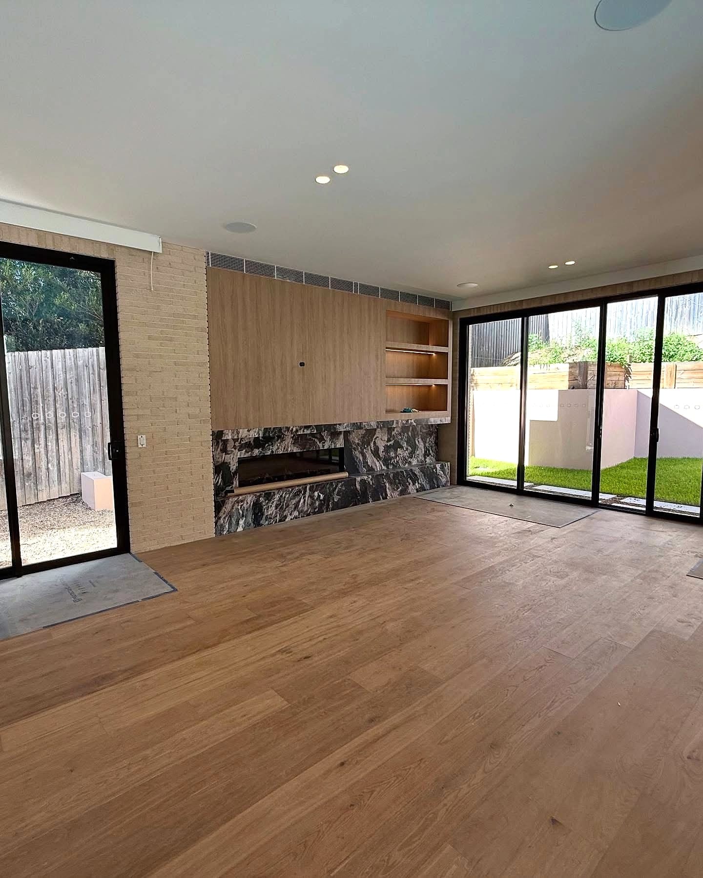Living room in plank flooring with a stone fireplace and glazing to the garden