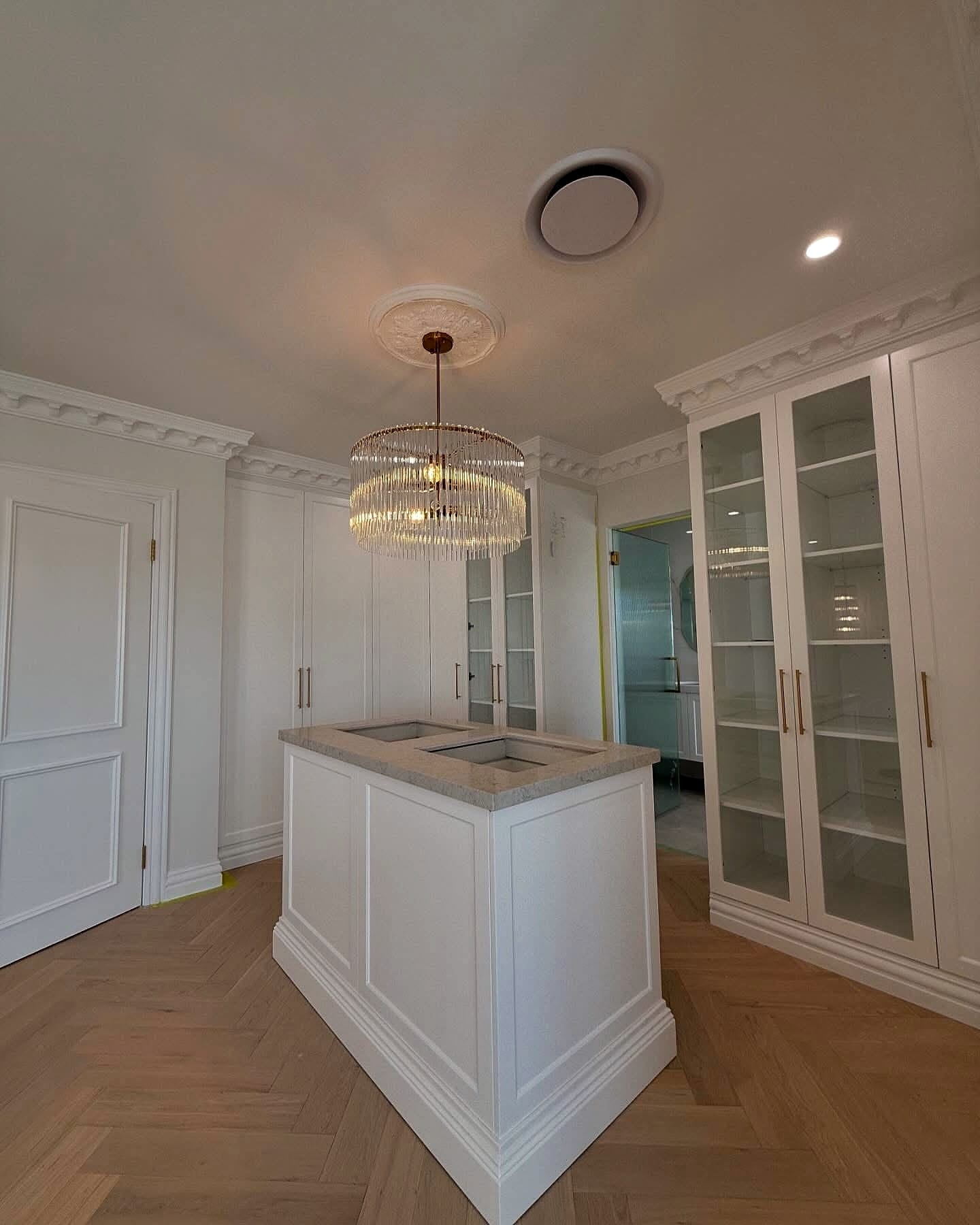 Kitchen with white joinery and a chandelier above a herringbone floor