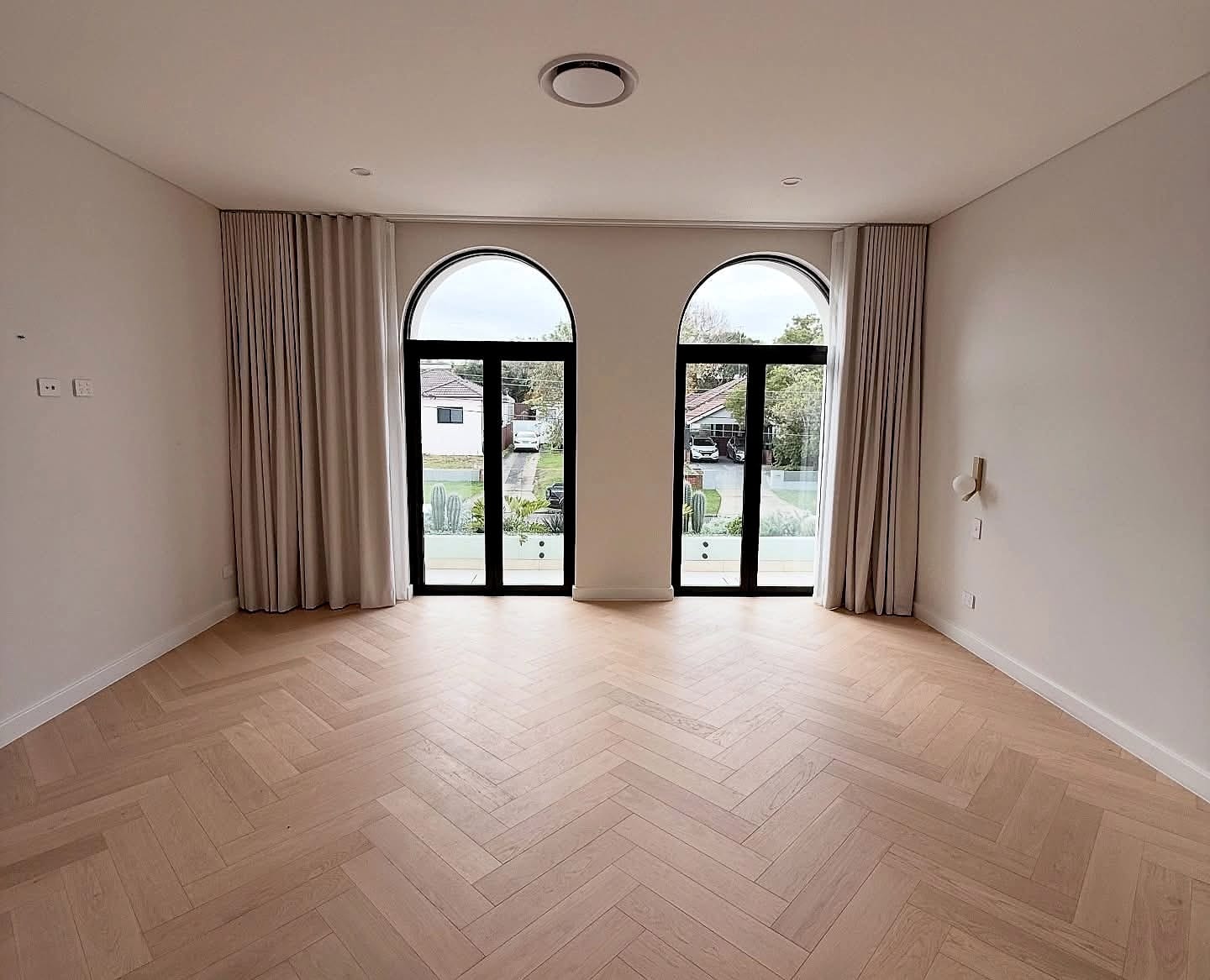 Room with arched glazed doors and curtains, herringbone flooring across the floor