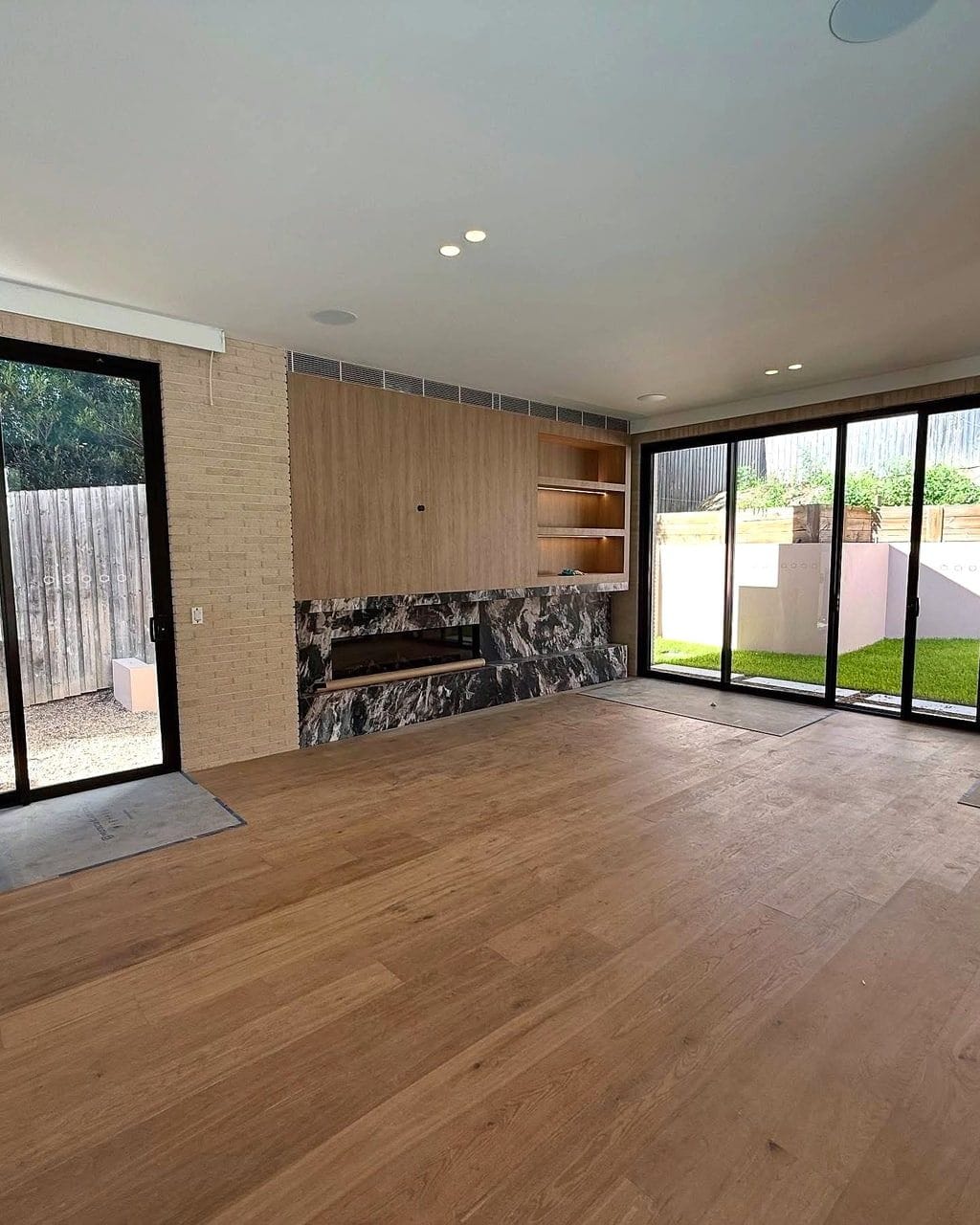 Wide oak planks laid in parallel runs across a living room with a stone fireplace